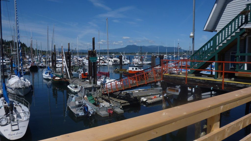 Boats moored at a marina in Cowichan Bay, British Columbia, with mountains across the water.